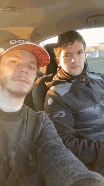 two men in a car one wearing a hat that says do on it