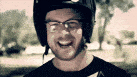 a man wearing a helmet and glasses smiles at the camera