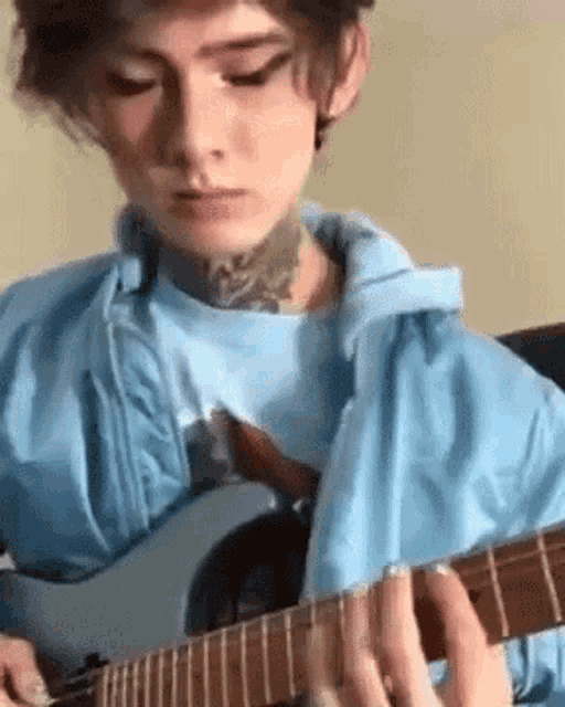 a young man is playing a guitar in a room .