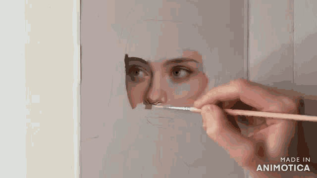 a person is painting a picture of a woman 's face with a brush ..