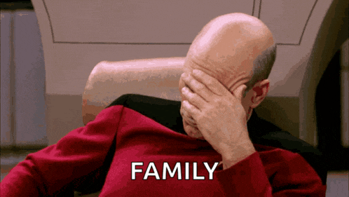 a man in a red shirt is covering his face with his hand and the word family is on the screen behind him