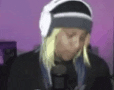 a man wearing a beanie and headphones is standing in front of a microphone .
