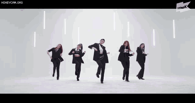 a group of women are dancing in front of a purple background with the k logo in the corner