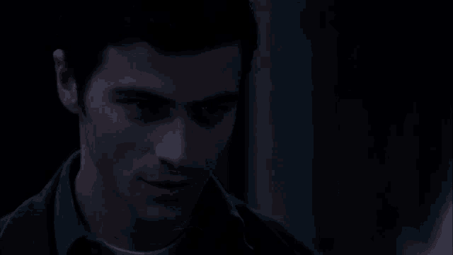 a man in a dark room is holding his finger to his lips