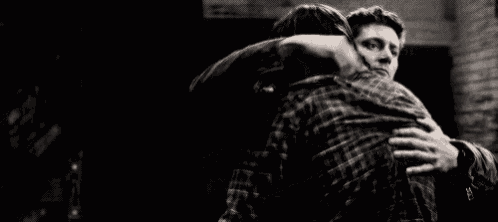 a black and white photo of a man hugging a woman .