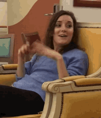 a woman in a blue sweater sits in a chair