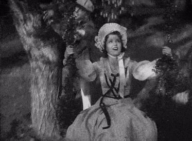 a woman in a white dress is swinging on a tree branch