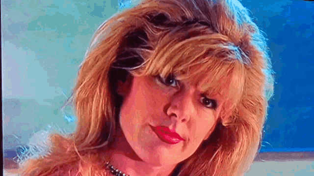 a close up of a woman 's face with blonde hair and red lipstick