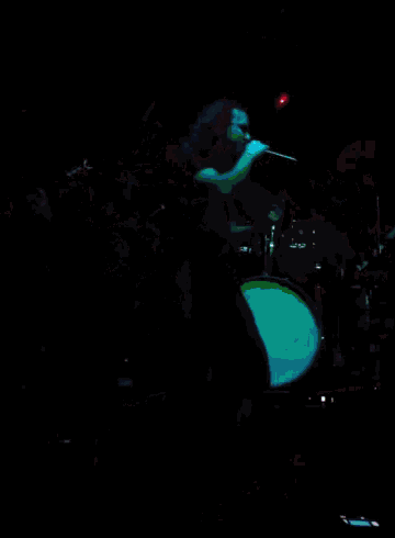 a man in a black shirt is playing a guitar on a stage