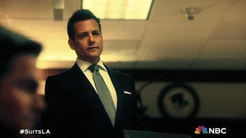a man in a suit and tie is standing in front of a nbc logo