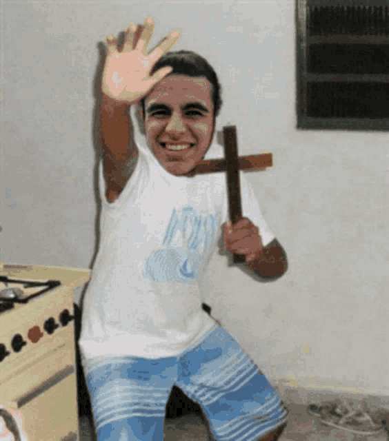 a man in a white shirt with the word jesus on it is holding a wooden cross