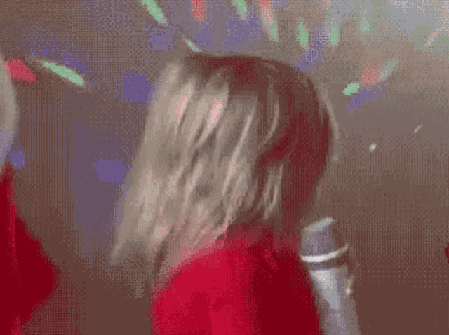 a woman in a red sweater is holding a microphone and making a funny face .