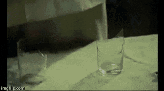 a broken glass is sitting on a table next to another glass