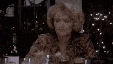 a woman is sitting at a table eating a piece of food with a spoon .