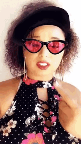 a woman wearing a black hat and red sunglasses is making a funny face