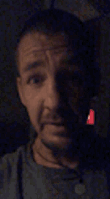 a close up of a man 's face in the dark with a red light shining on his face .