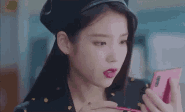 a woman is looking at herself in a mirror while holding a cell phone .