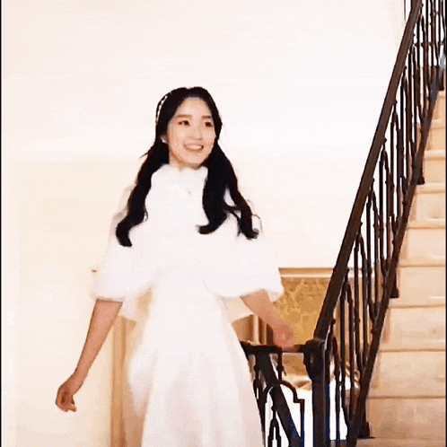 a woman in a white dress is walking up a set of stairs