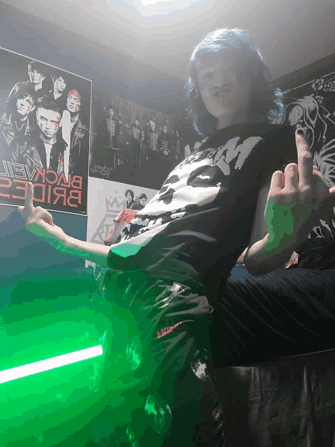 a person giving the middle finger in front of a poster that says " black veil "