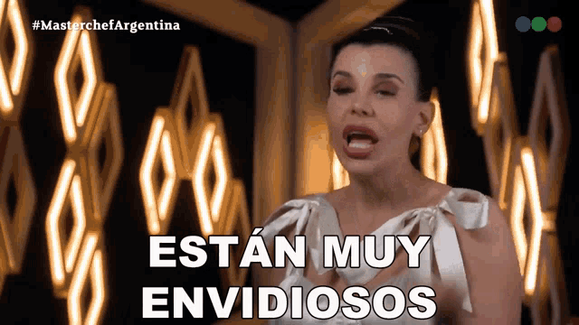 a woman says " estan muy envidiosos " in front of a wall of lights
