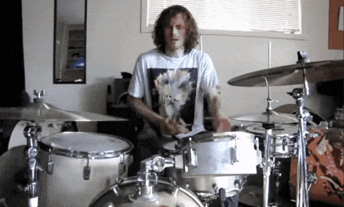 a man playing drums in a room with a mirror
