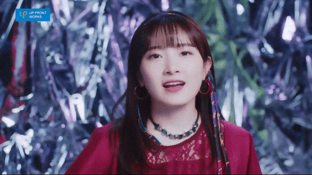 a girl in a red top is standing in front of a shiny background with the letters lp on the bottom