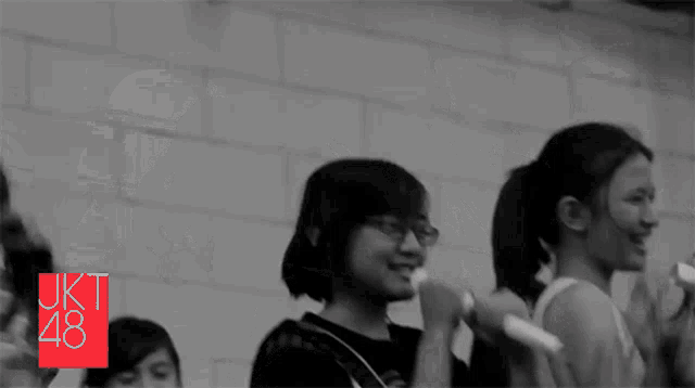 a group of people are standing in front of a brick wall with the letters jkt 48 on the bottom