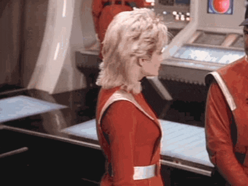 a woman in a red space suit is standing next to a man in a red suit .