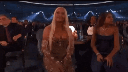 a woman in a dress is sitting in the audience at a concert .