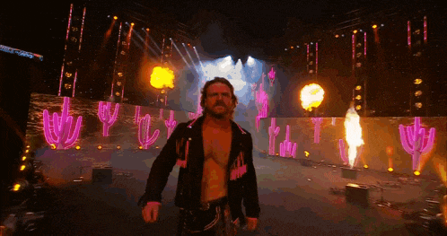 a man without a shirt is walking on a stage with flames coming out of the ceiling .