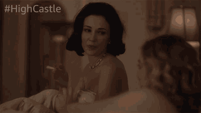 a woman smoking a cigarette next to another woman with #highcastle on the bottom right