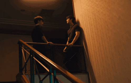 two men are standing on a set of stairs talking to each other