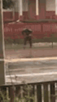 a person is walking in the rain with an umbrella in front of a house .