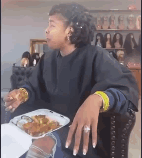 a woman is sitting in a chair eating a tray of food .