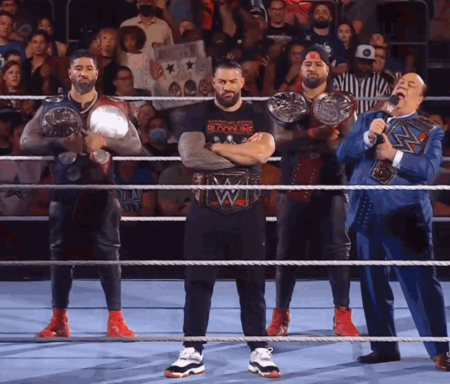 a group of men standing in a wrestling ring with one wearing a t-shirt that says bloodline