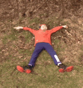 a person laying on the ground with their arms outstretched and a red shirt on
