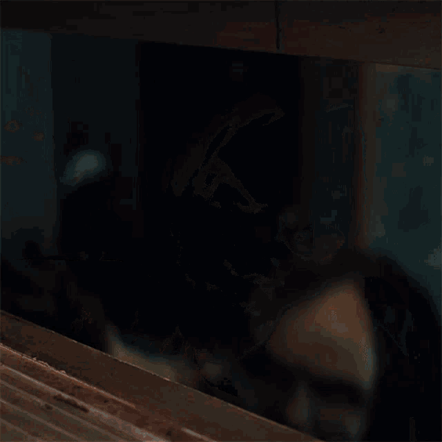 a woman with a scary face is coming out of a doorway in a dark room .