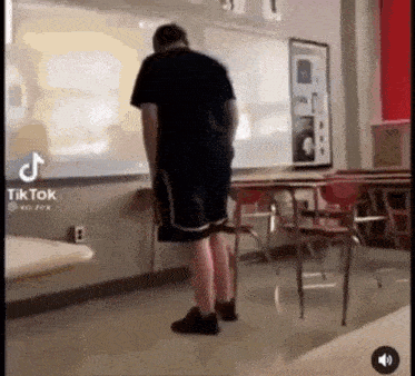 a man is standing in a classroom next to a whiteboard .