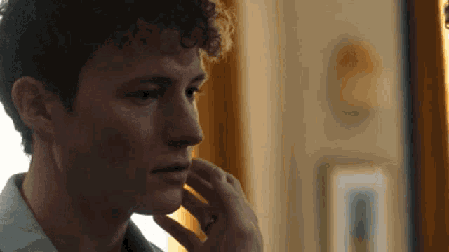 a man with curly hair is looking at himself in the mirror