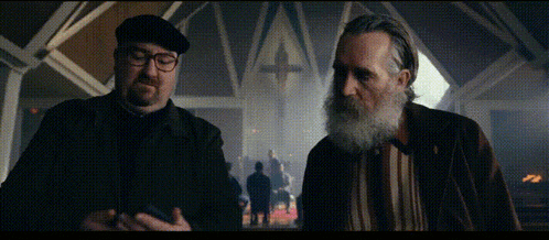 a man with glasses and a beard stands next to another man