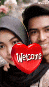 a man and a woman are posing for a picture with a red heart that says welcome