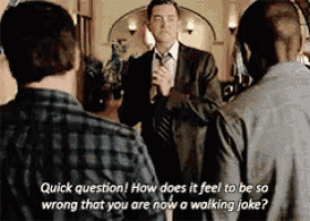 a man in a suit and tie is talking to another man in a plaid shirt