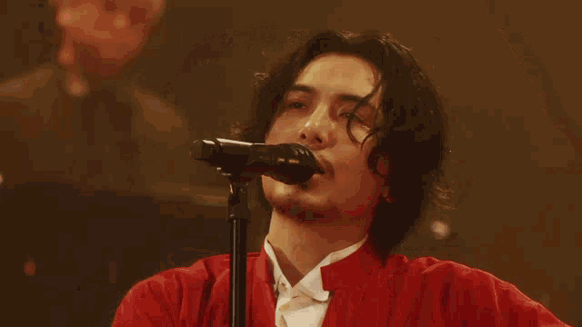a man singing into a microphone with his arms in the air