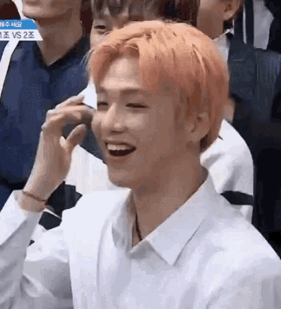a young man with orange hair is laughing in a crowd of people .