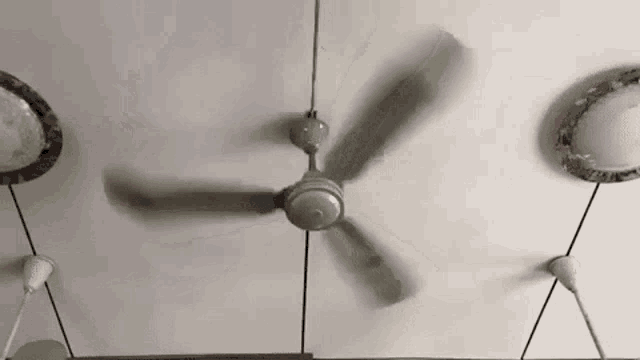 a ceiling fan is spinning on a ceiling in a room .