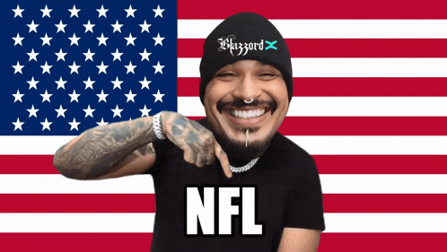 a man wearing a beanie and a shirt that says nfl points to the camera