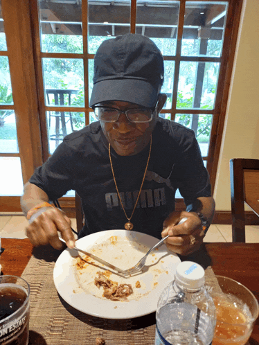 a man wearing a black puma shirt sits at a table