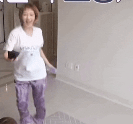a woman in a white shirt and purple pants is standing on a tiled floor .
