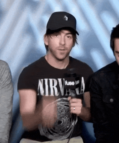 a man wearing a nirvana t-shirt holds a microphone