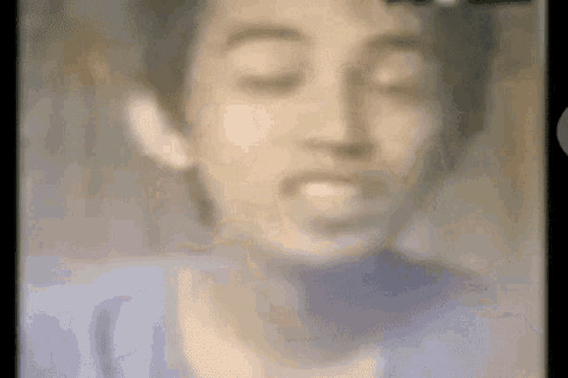 a blurry picture of a young man 's face with his eyes closed .